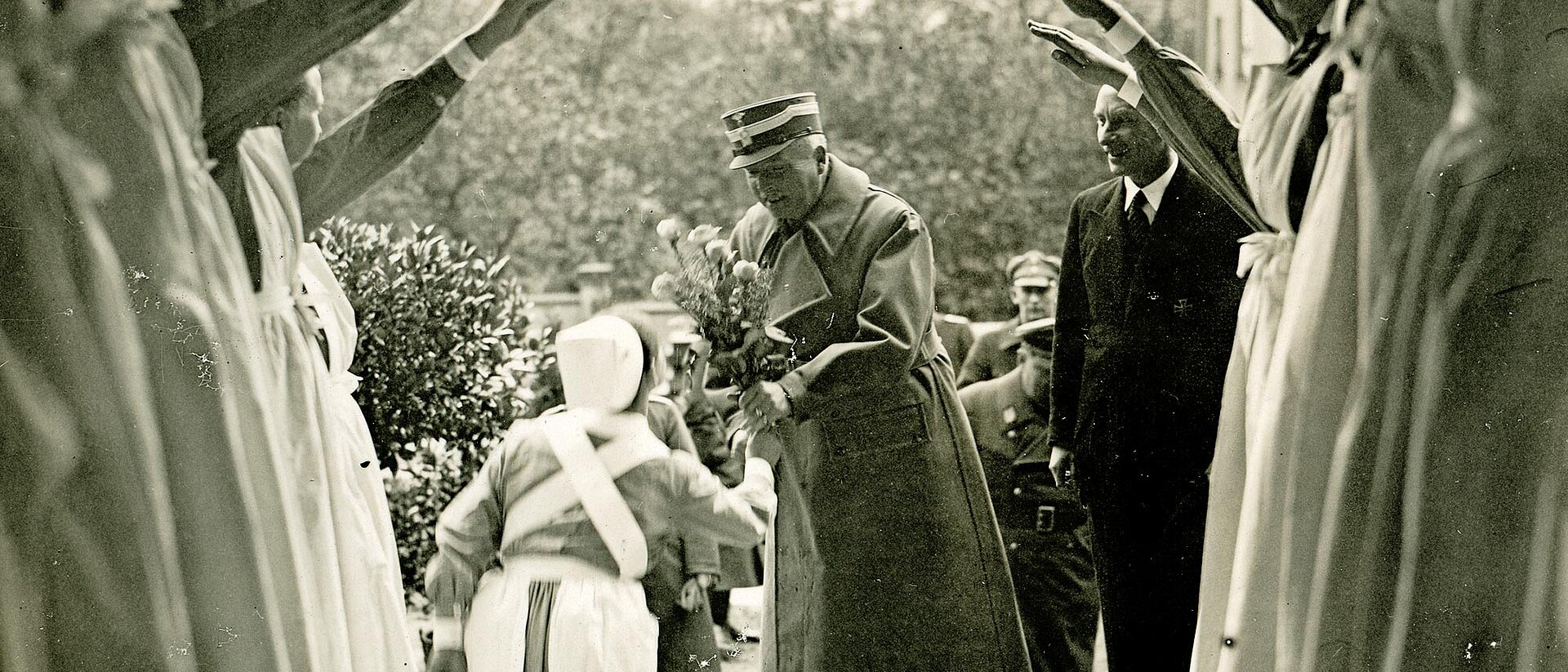 Begrüßung des DRK-Präsidenten 1935 Schwesternhelferin übergibt Mann Blumen