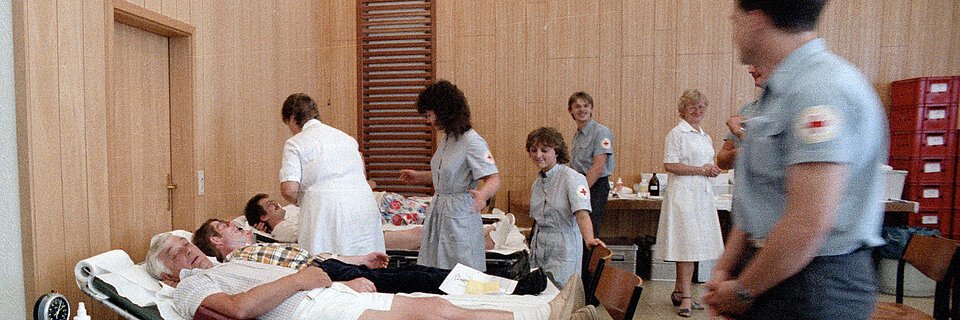 Blutspendedienst des DRK Rotkreuzlerinnen nehmen Blut von Spendern - 80er Jahre