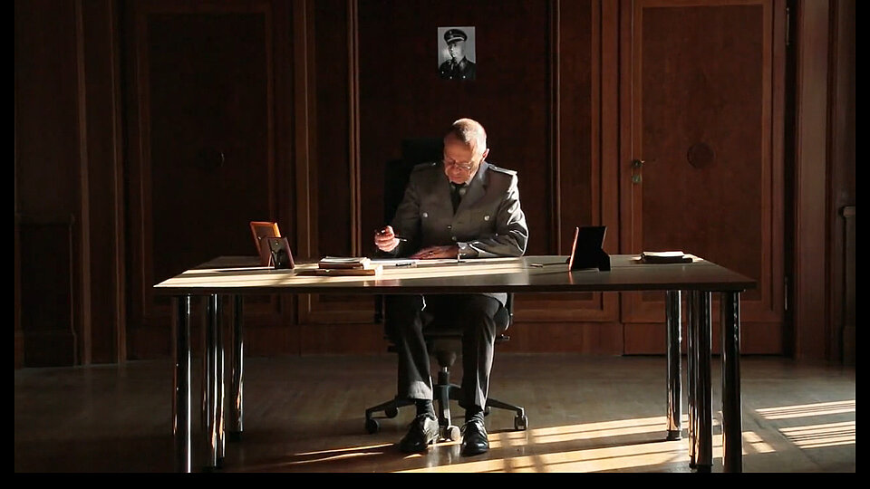 Mann in Uniform sitzt an Schreibtisch