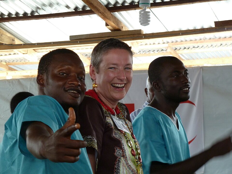 Ebolahelfer in Liberia Zwei linberianische Kollegen in blauen Kitteln stehen neben Regine Reim
