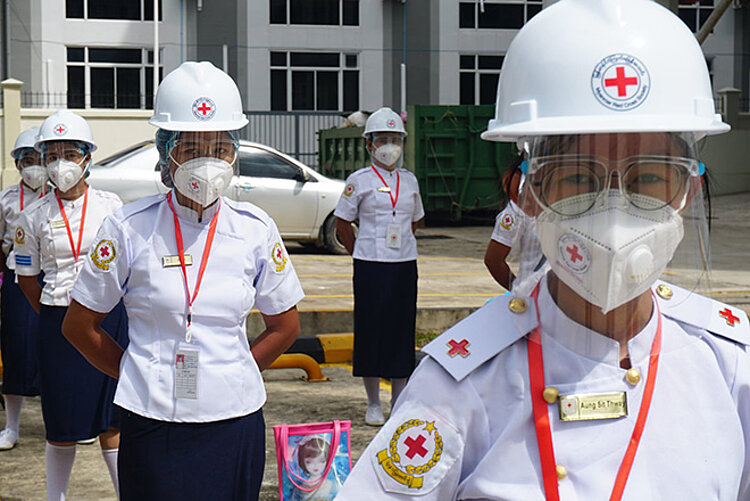 Freiwillige mit Infektionsschutzausrüstung Freiwillige des Myanmarischen Roten Kreuzes in Uniform und Infektionsschutzausrüstung