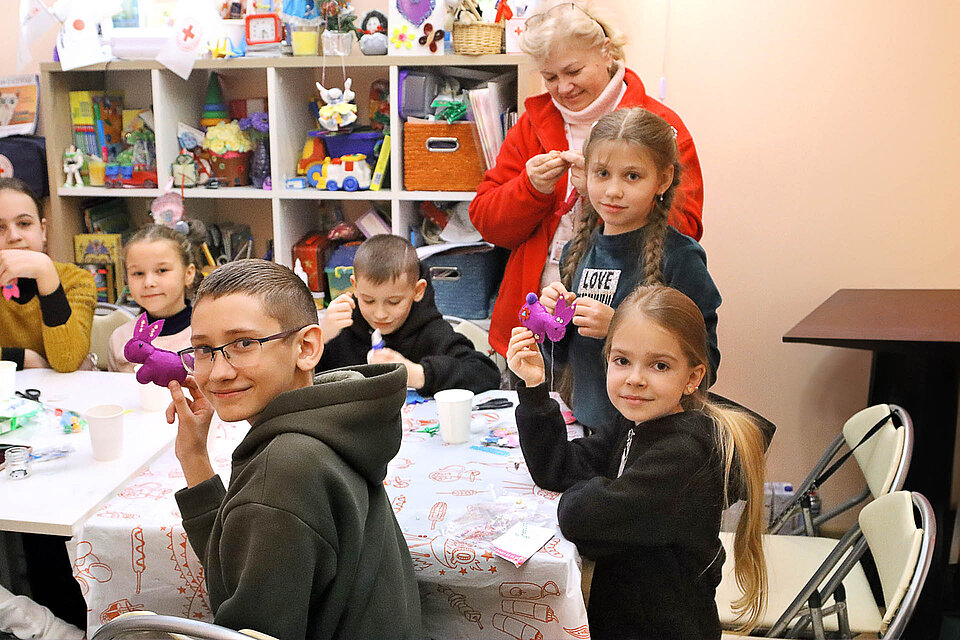 Kindergruppe mit Rotkreuzlerin beim Basteln