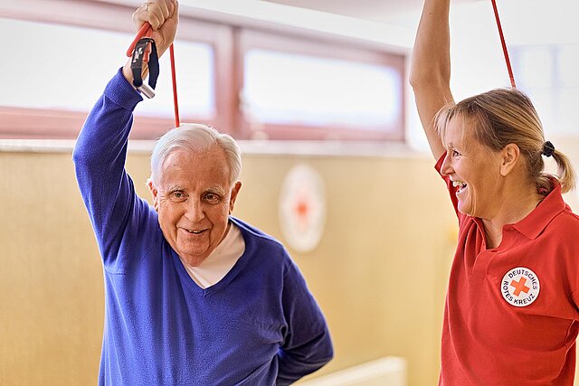 Senior und DRKlerin bei Gymnastik mit Expander