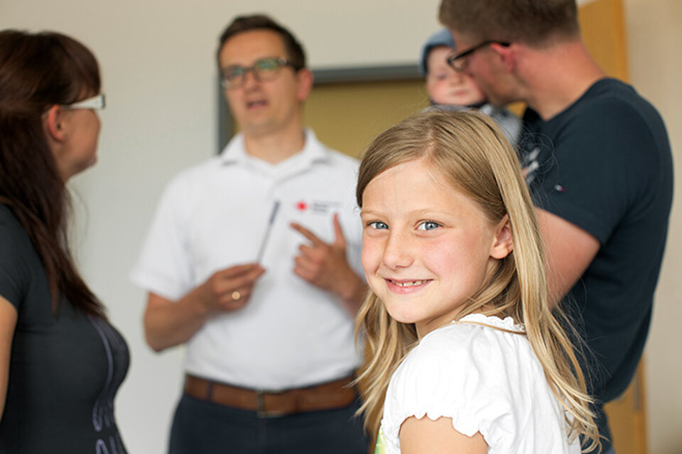 Kinderwohl Mädchen mit Elterngespräch im Hintergrund