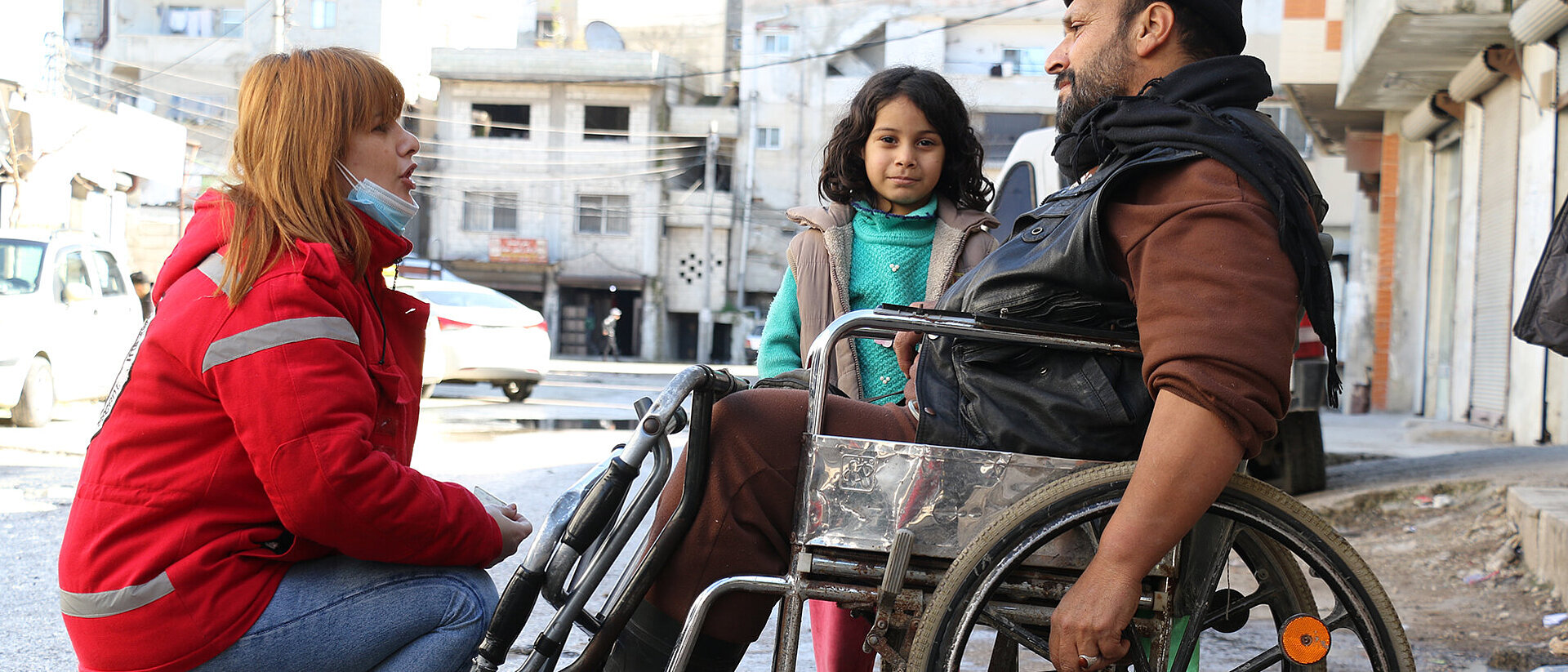 Syria: Humanitarian Aid Volunteer speaking with man in wheelchair
