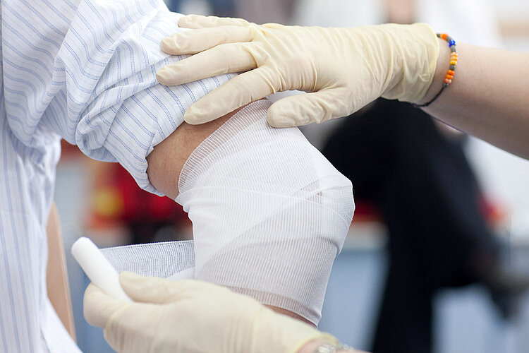 Erste Hilfe Ellbogenverband und Hände in Gummihandschuhen
