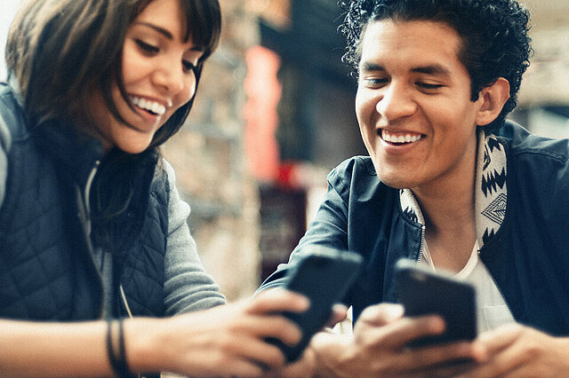 Foto: Mann und Frau im Gepräch - auch ihre Mobiltelefone schauend