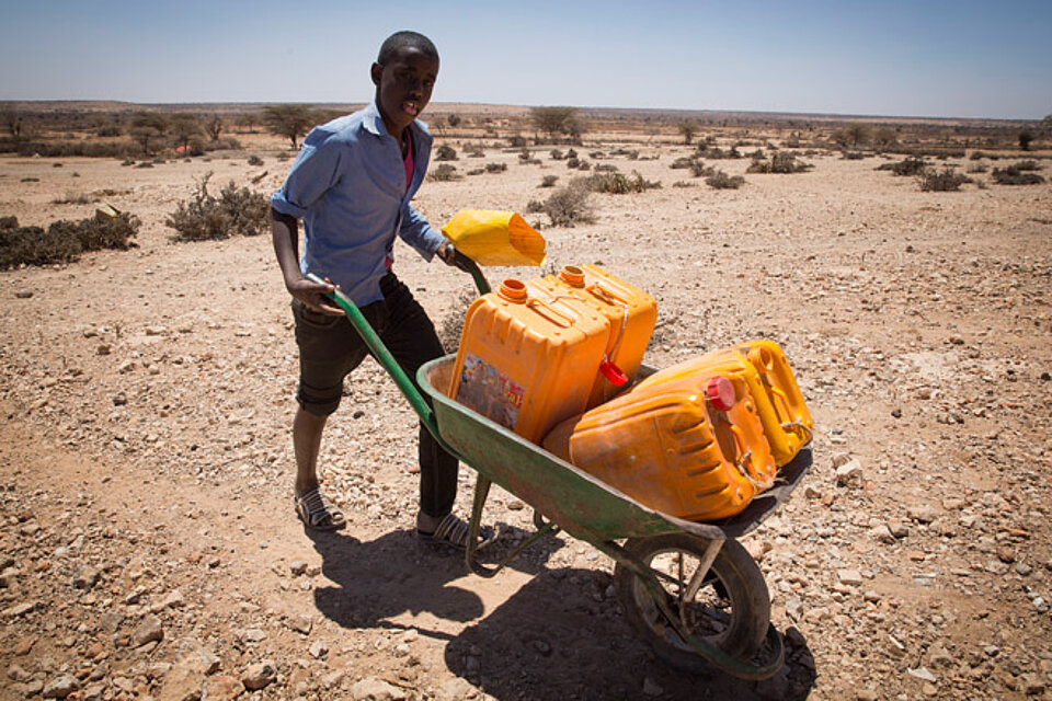 Nothilfe des DRK zusammen mit der Deutschen Bank in Somalia Ein somalischer Junge transportiert Wasserkanister mit einer Schubkarre in der Wüste