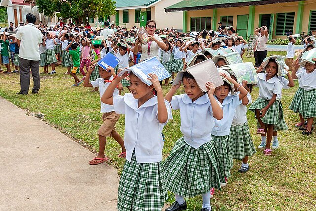 Kinder schützen ihre Köpfe mit Schulheften