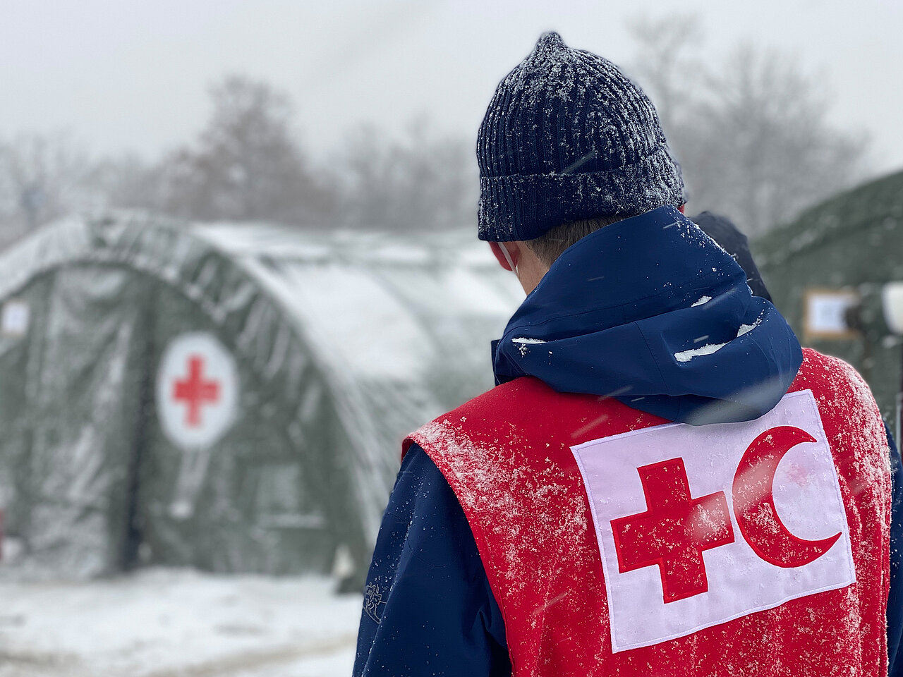 Red Cross volunteer and tent in snow