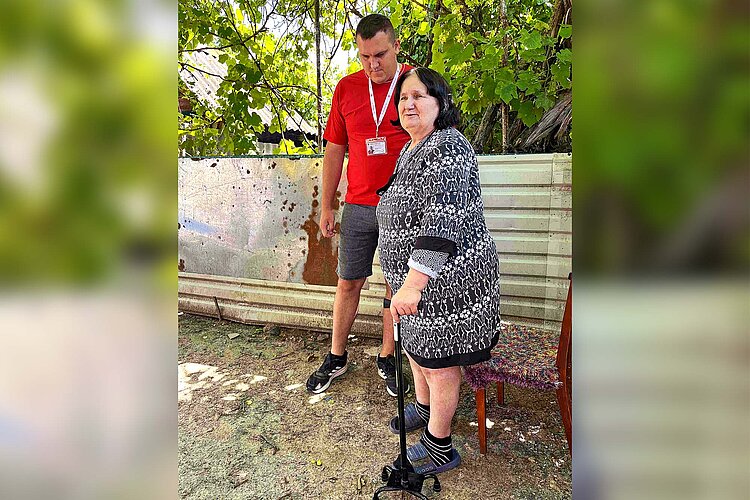 Rotkreuz-Hilfe in der Ukraine Rotkreuzler und Seniorin mit Krücke