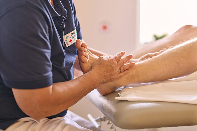 Therapeut massiert Füße eines Patienten