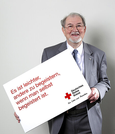 Dr. Christoph Brückner Christoph Brückner hält Schild mit Slogan einer DRK-Kampagne