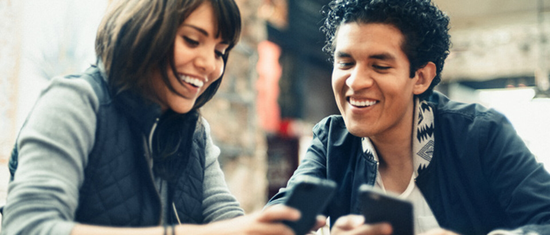 Foto: Mann und Frau im Gespräch - auf ihre Mobiltelefone schauend