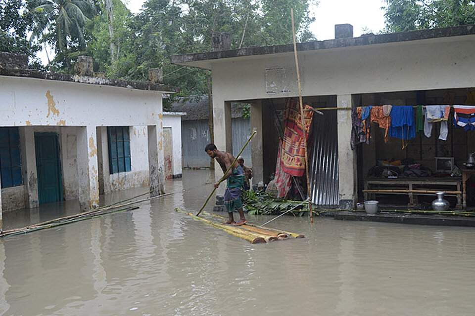 Vorhersagebasierte Finanzierung als Hilfe in Bangladesch Ein Mann auf einem Floß in den überfluteten Straßen