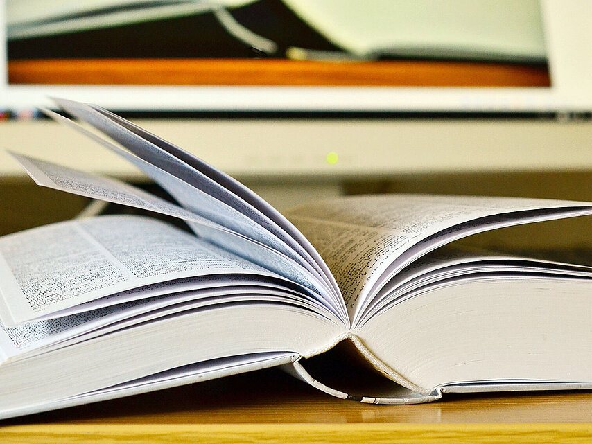 Geöffnetes Buch vor Bildschirm