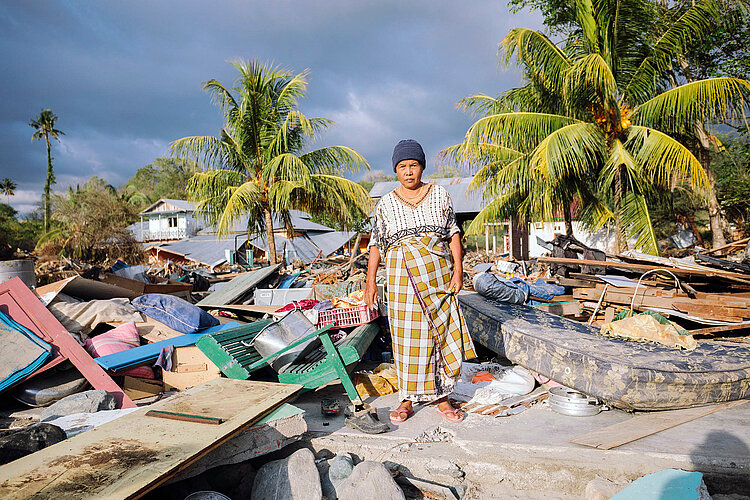 Erdbeben und Tsunami in Indonesien Seniorin steht auf Trümmern vor Palmen
