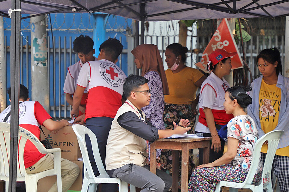 Rotkreuzhelfer spricht mit Patientin in mobiler Gesundheitsstation in Myanmar 
