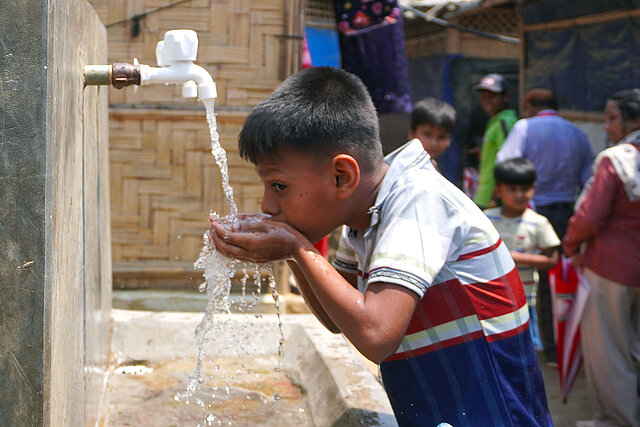 Junge trinkt an Wasserstelle