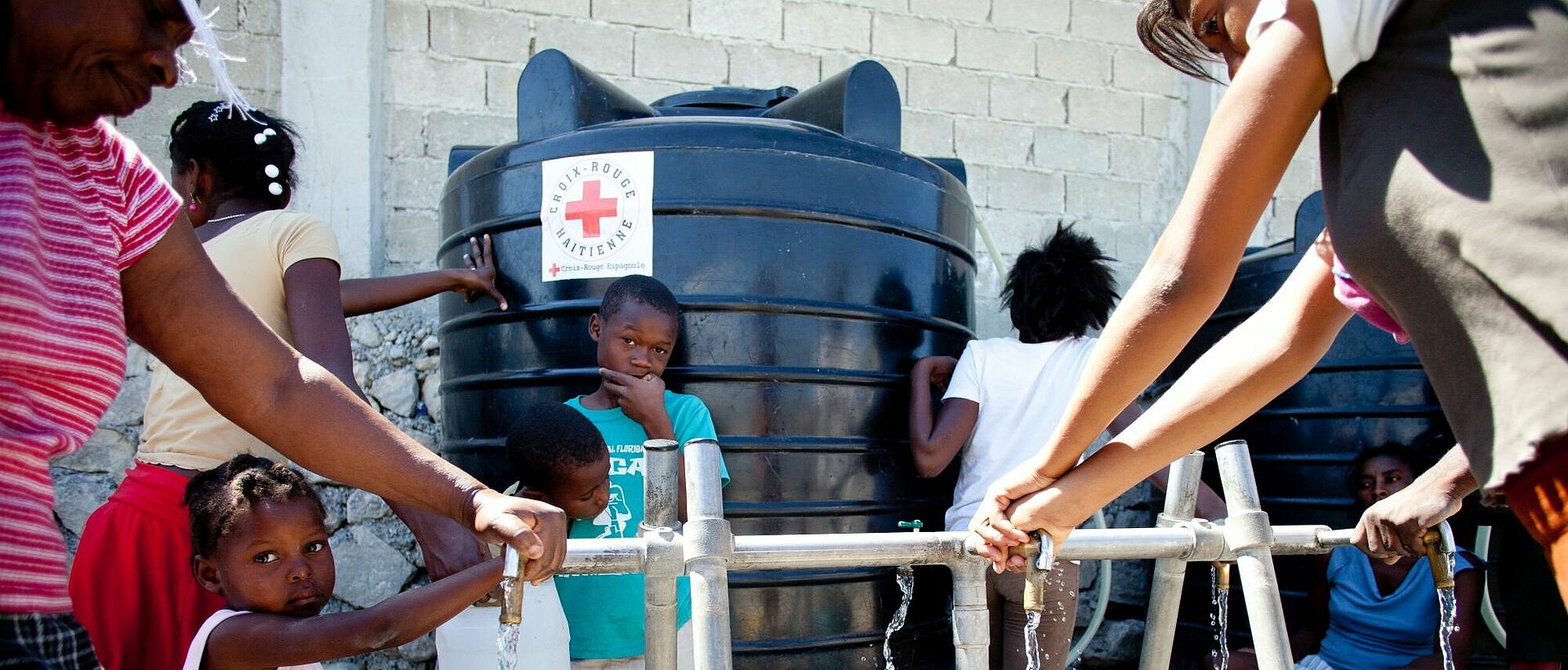 Humanitäre Hilfe in Haiti Menschen auf Haiti nutzen eine Wasserquelle