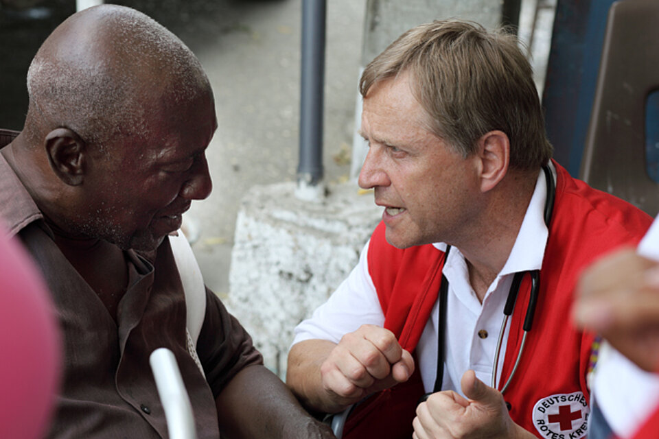 Foto: hauslebensabend.livelegierter spricht mit einem älteren Mann in Haiti.