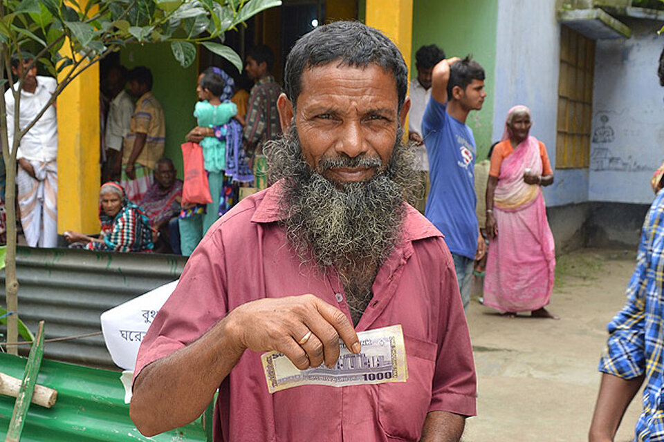 Hilfe in Bangladesch mit vorhersagebasierter Finanzierung Ein bengalischer Mann mit einem Geldschein