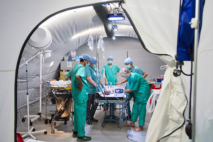 OP im mobilen Krankenhaus Medizinisches Personal in Schutzkleidung bei OP