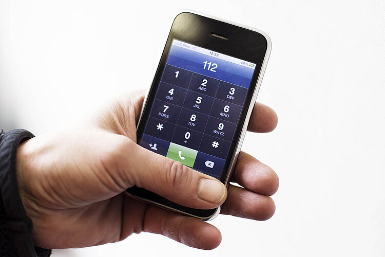 Notruf: Eigenes Telefon Hand hält Telefon mit Notrufnummer