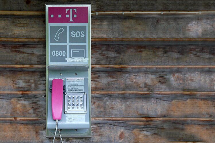 Notruf: Öffentliches Telefon Öffentliches Telefon mit Notrufaufschrift an Holzwand