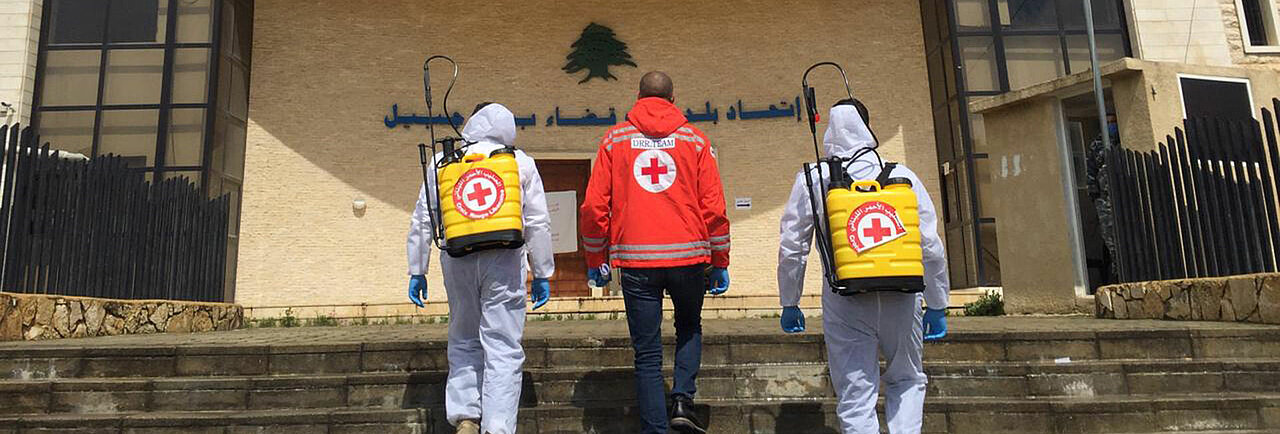 Hilfe gegen die Ausbreitung von Corona im Libanon Drei Helfer des Roten Kreuzes mit Desinfektionssprühern gegen die Ausbreitung von Corona im Libanon