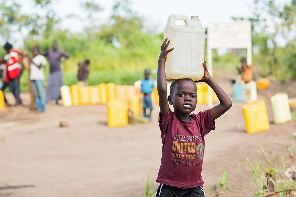 DRK-Hilfe in Uganda Junge trägt Wasserkanister auf Kopf