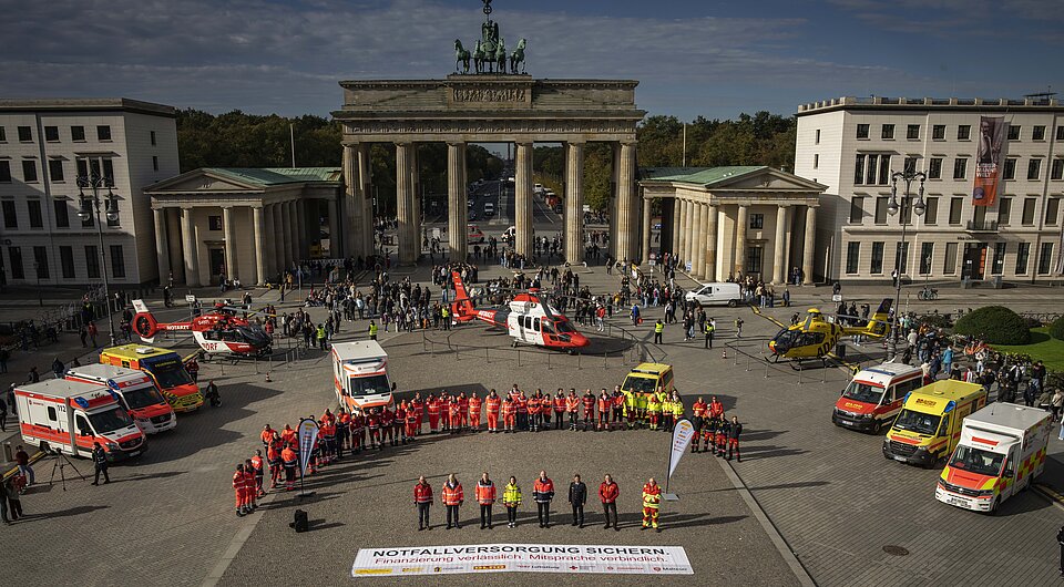 Blick von oben auf das Brandenburger Tor. Davor stehen mehrere Personen in Einsatzkleidung vor mehreren Rettungshubschraubern und Rettungswagen