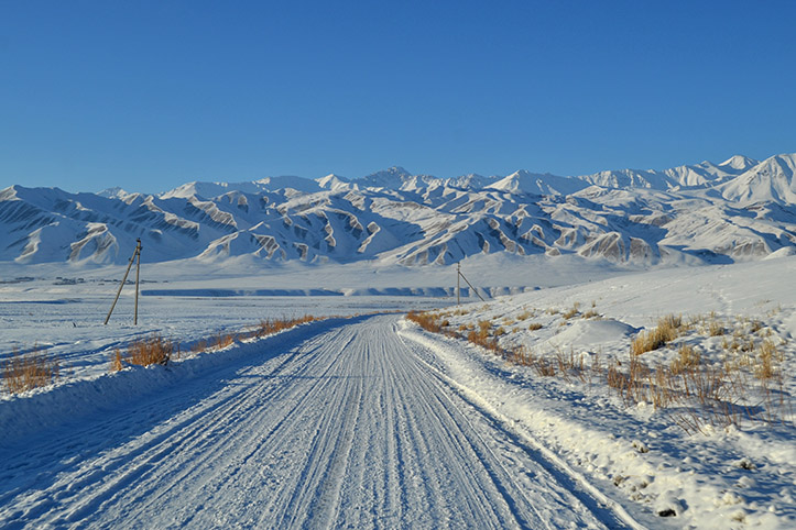 Winterliche Straße verschneite Straße vor kirgisischen Bergen